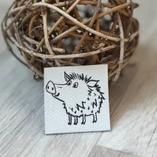 Koženkový štítek s ježatým divočákem na bílém podkladu