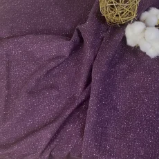 Detail fialové teplákoviny s třpytivým tiskem hvězdného prachu, jednorožci, květinami a pohádkovými zámky.