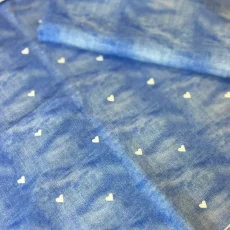 Balíček látky s denimovým vzhledem a jemným potiskem bílých srdíček, ideální na dětské oblečení nebo doplňky. Balíček látky s denimovým vzhledem a jemným potiskem bílých srdíček, ideální na dětské oblečení nebo doplňky.