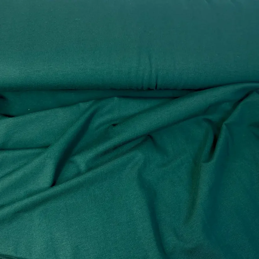 Detail tmavě zeleného bio organického single-jersey úpletu s jemnou hladkou strukturou.