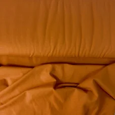 Detail bio organického single-jersey úpletu v jemné karamelové barvě.