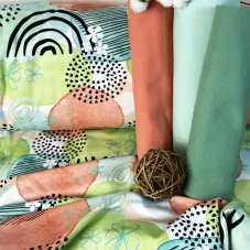 Nepočesaná teplákovina s abstraktním vzorem v pastelových barvách – zelená, lososová a tyrkysová s černobílými grafickými prvky.