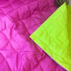 Prošívaná látka ve výrazné růžové a žlutozelené barvě – detail povrchu a struktury.