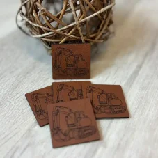 Koženkové štítky s motivem bagru – detailní gravírování na hnědé kožence, ideální doplněk k teplákovině se stavebními stroji.