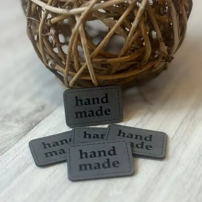 Šedý koženkový štítek s nápisem handmade