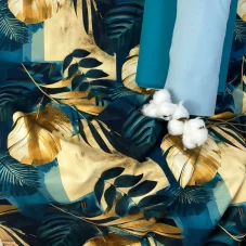 Detail nepočesané teplákoviny s tropickým motivem palmových listů v petrolejové, tyrkysové a zlaté barvě, doplněné o náplety a vatovou bavlnu.