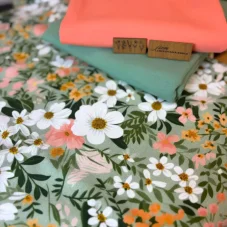 Jarní balíček látek s květinovým potiskem v pastelových barvách doplněný o úplety v barvách meruňky a šalvějové zeleně a koženkovým štítkem „jsem limitovaná edice“.