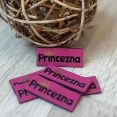 Růžový koženkový štítek s nápisem Princezna a zlatou korunkou – detail produktu.