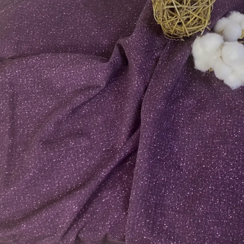 Detail fialové teplákoviny s třpytivým tiskem hvězdného prachu, jednorožci, květinami a pohádkovými zámky.