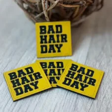 Koženkový štítek BAD HAIR DAY ve žluté barvě s černým nápisem – detail produktu.
