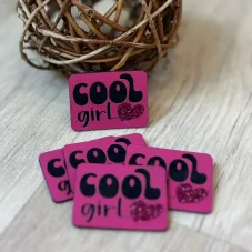 Růžový koženkový štítek s nápisem Cool Girl a třpytivým srdíčkem – detail produktu.