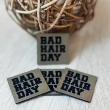 Koženkový štítek BAD HAIR DAY v antik hnědé barvě s černým nápisem – detail produktu.