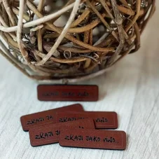 Hnědý koženkový štítek s nápisem Zraji jako víno – detail produktu.